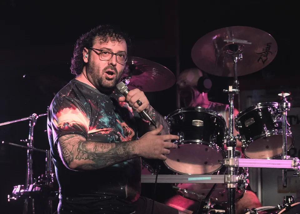 The drummer of Emulsified mid-song, lit in purple