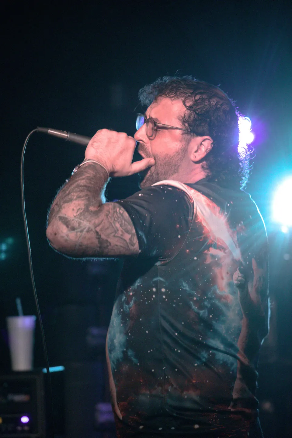 The singer of Emulsified under teal stage light