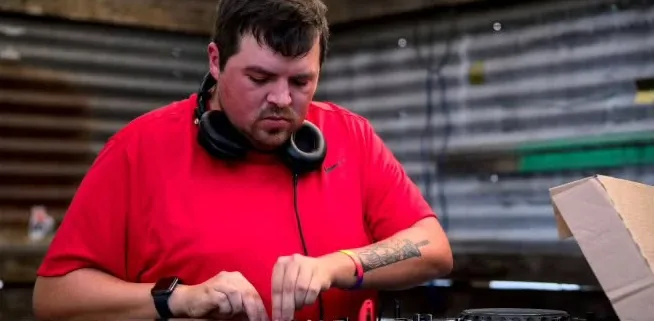 A DJ in a red shirt working the mixer at The Spot