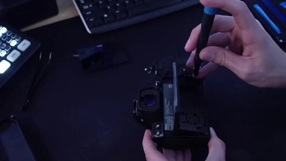 Hands removing screws from the back of a Nikon Z5 camera during a screen replacement