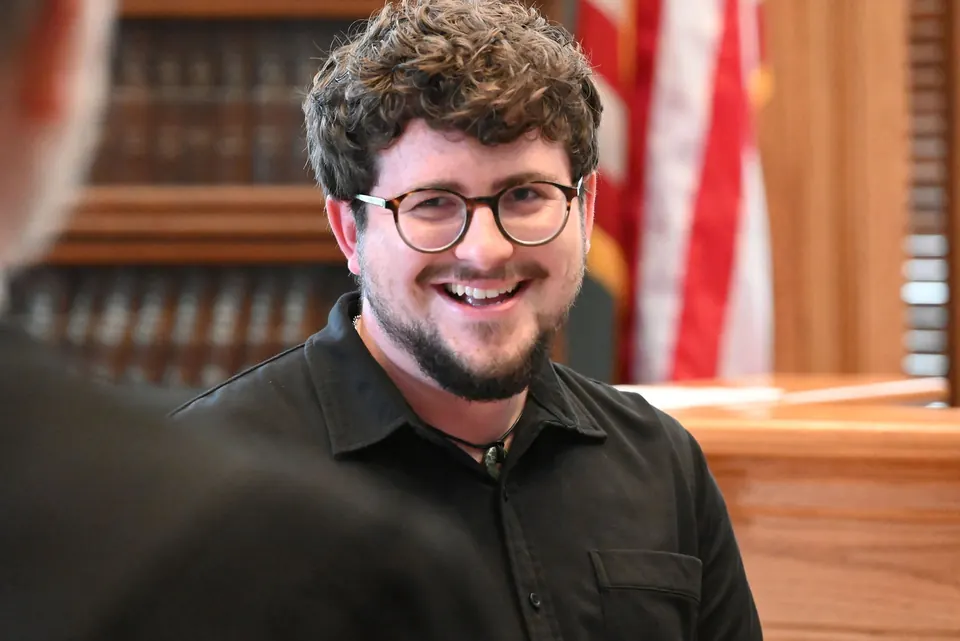 Ethan smiling in the courtroom, with Aaron beside him