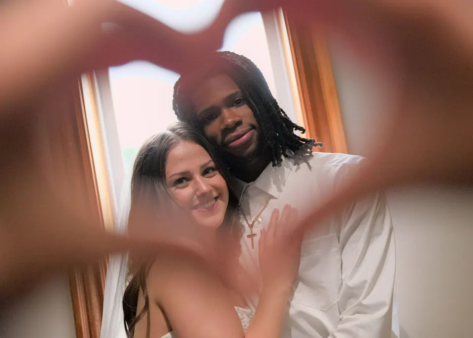 Kassie and Noah framed by a heart made with someone’s hands